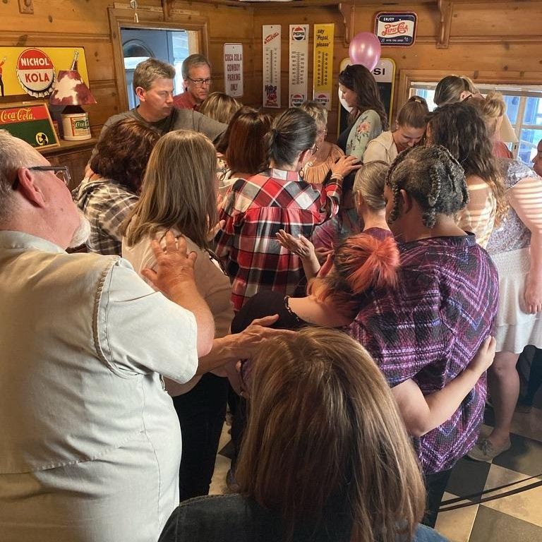 Photo of the community praying for our recent graduate