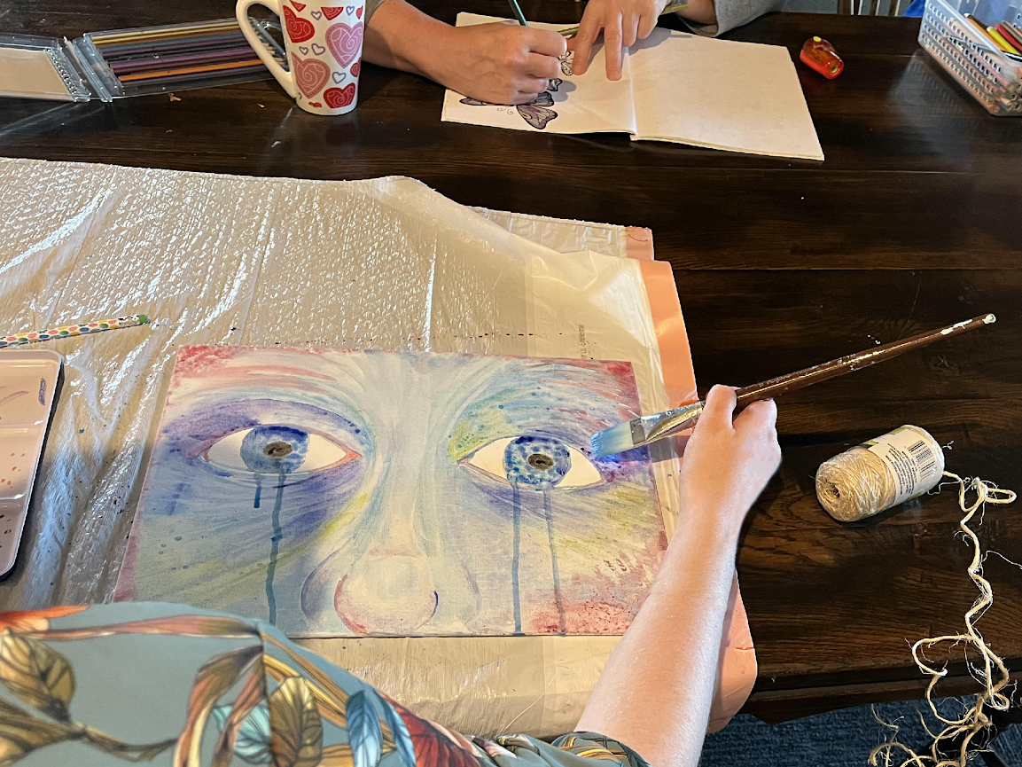 Photo of a painting by a resident of Hope Ranch; watercolor; a close up of two eyes gaze out at the viewer with blue tears streaming off the page.